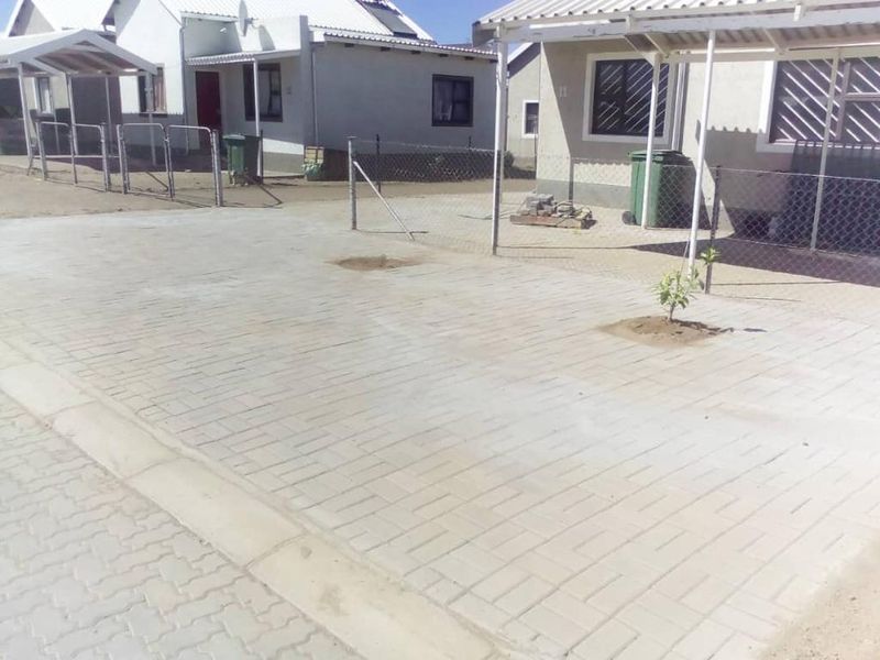 A paved front driveway area featuring a carport structure and chain link perimeter fencing in a residential townhouse setting.