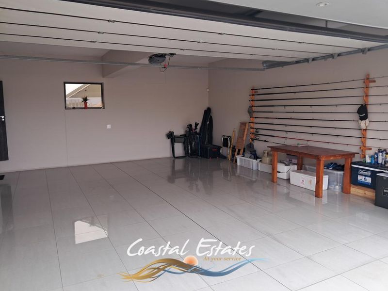 Spacious, well-maintained garage featuring polished tiled flooring, recessed lighting, and integrated wall-mounted storage systems.