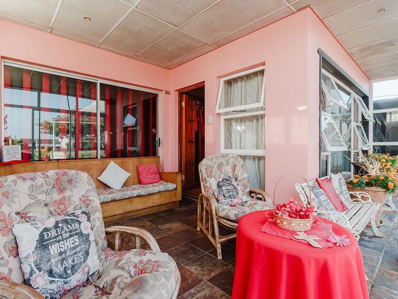 A covered patio area featuring tiled flooring, built-in bench seating, and large windows, offering a potential space for outdoor relaxation and entertainment.