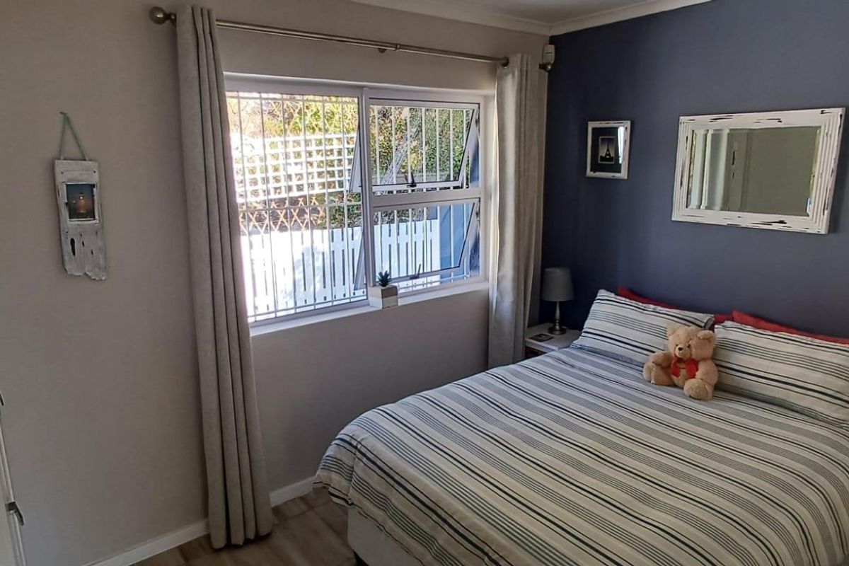 A cozy bedroom featuring a window with security bars, built-in wardrobe, and neutral flooring.