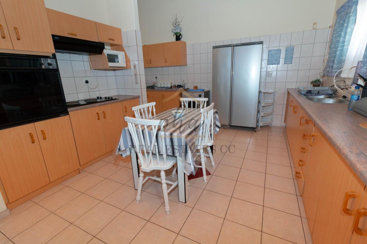 A functional kitchen featuring laminate cabinetry, built-in oven, hob, extractor fan, and tiled finishes throughout.