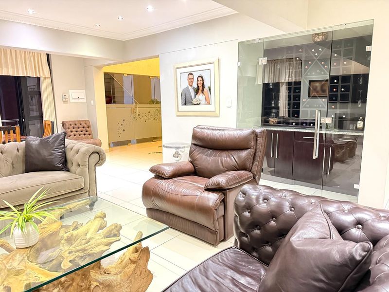 Spacious living area featuring tiled flooring, recessed lighting, and a modern glass-enclosed wine cellar.