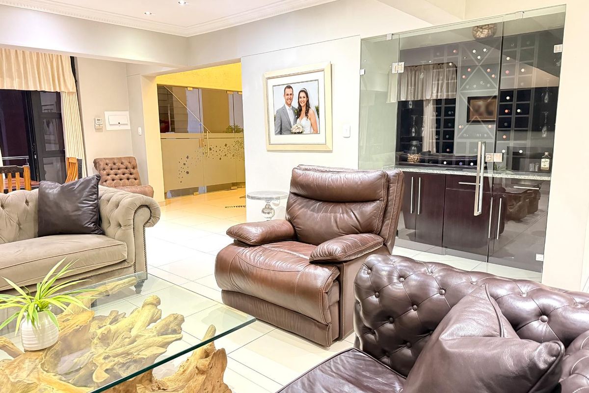 Spacious living area featuring tiled flooring, recessed lighting, and a modern glass-enclosed wine cellar.