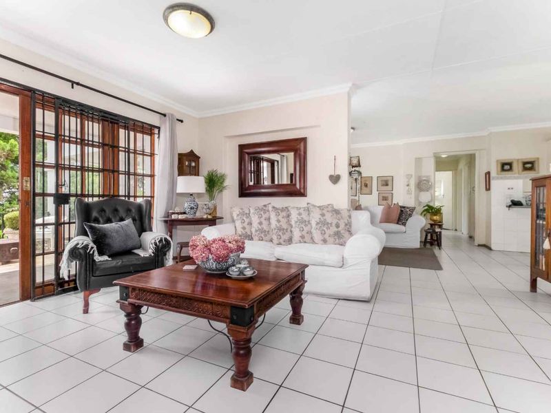 Spacious living room featuring tiled flooring and a sliding glass door with security gate, providing access to the outdoor patio area.