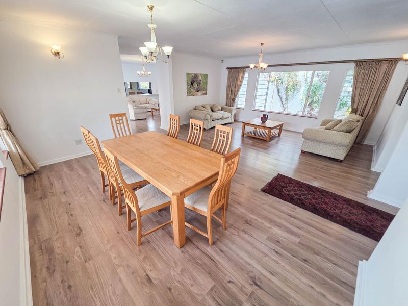 Spacious open-plan living and dining area featuring modern laminate flooring, large windows providing natural light, and neutral wall finishes.