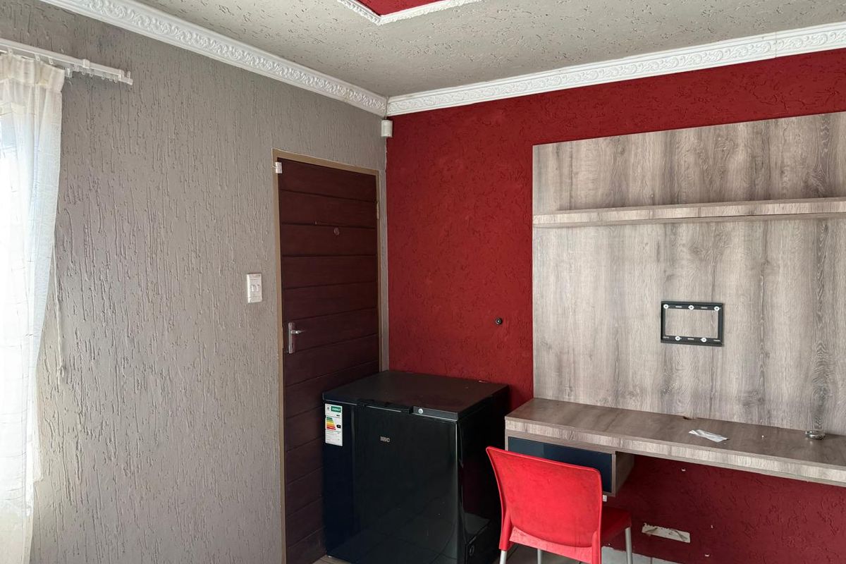A bedroom featuring a built-in desk unit, decorative ceiling cornices, and textured wall finishes in a contrasting red and grey color scheme.