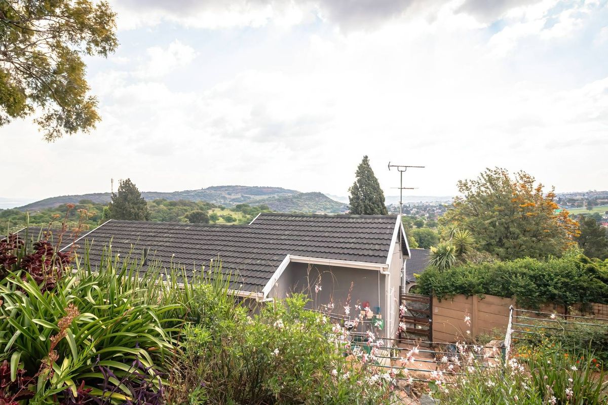 Rear view of the property featuring a tiled roof and expansive views of the surrounding landscape and neighborhood.