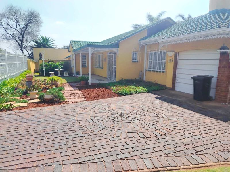Front view of a single-story house featuring a circular paved driveway, covered porch entrance, and a single garage with a tiled roof.