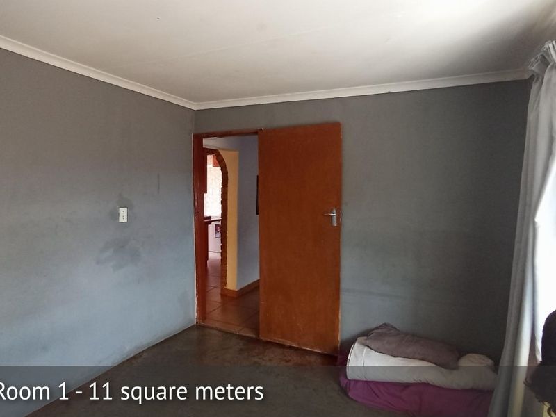 A compact bedroom featuring grey painted walls, a wooden door, and cove cornicing, offering a blank canvas for potential interior updates.