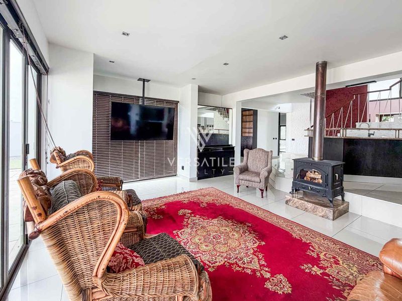 Spacious living area featuring a freestanding fireplace, large sliding glass doors providing natural light, and a staircase with a modern metal railing.