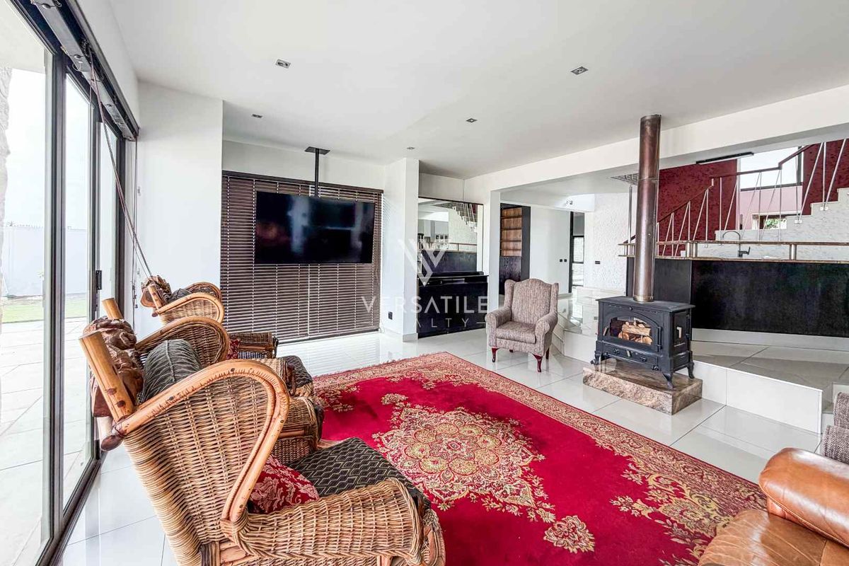 Spacious living area featuring a freestanding fireplace, large sliding glass doors providing natural light, and a staircase with a modern metal railing.