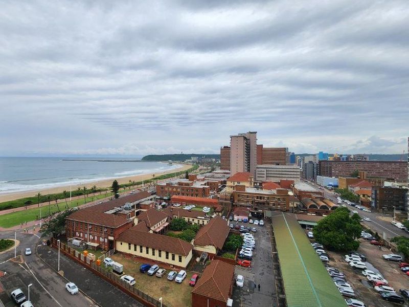 Elevated coastal view overlooking the city skyline, beach, and surrounding urban infrastructure.