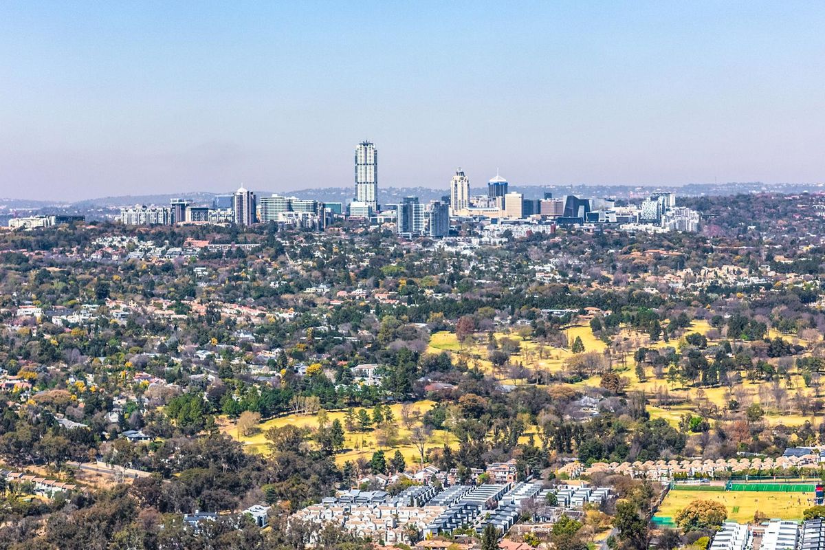 An expansive aerial view showcasing the surrounding landscape, residential areas, and the distant city skyline.