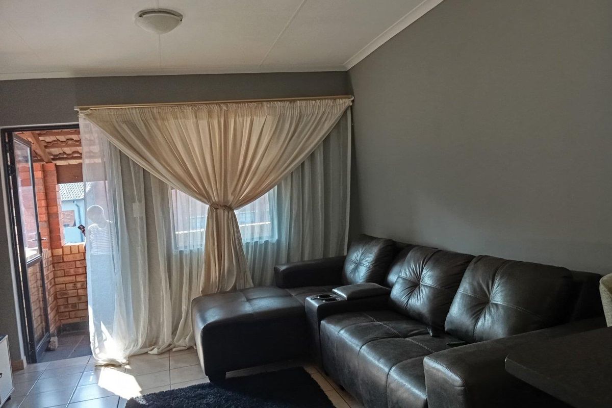 A living room area featuring tiled flooring and a sliding glass door providing access to an outdoor space.