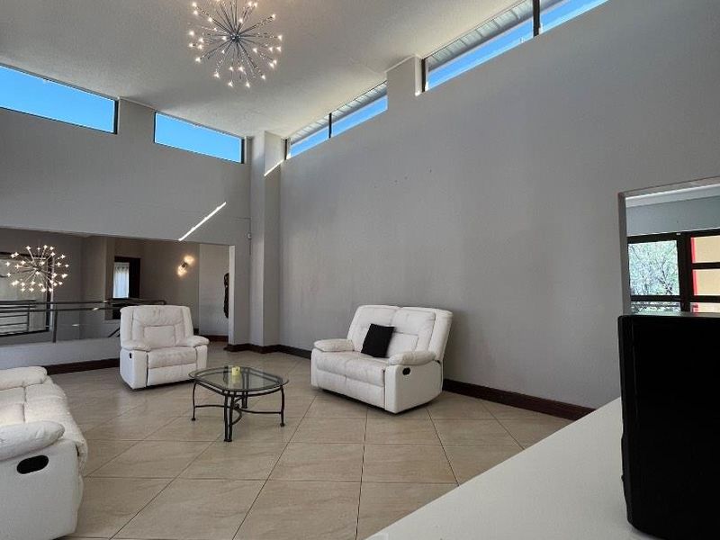 Spacious living room featuring high ceilings, clerestory windows for natural light, and neutral tiled flooring.