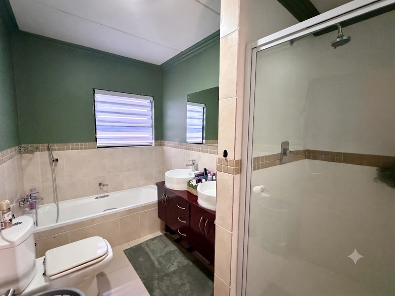 A well-maintained bathroom featuring a built-in bathtub, separate shower enclosure, and a dual vanity with vessel sinks.