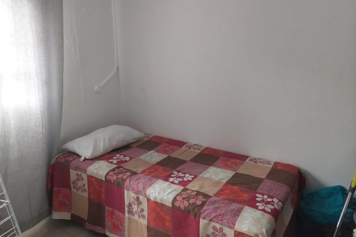 A compact bedroom featuring tiled flooring and surface-mounted electrical conduit along the wall.