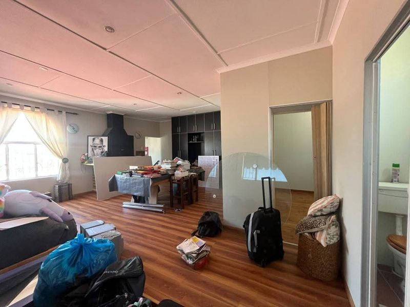 A living area featuring laminate flooring, built-in cabinetry, and a tiled ceiling, offering a functional space with potential for modernization.