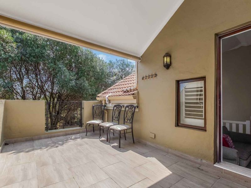 A covered balcony featuring tiled flooring, a wall-mounted light, and access to the interior through a sliding glass door.