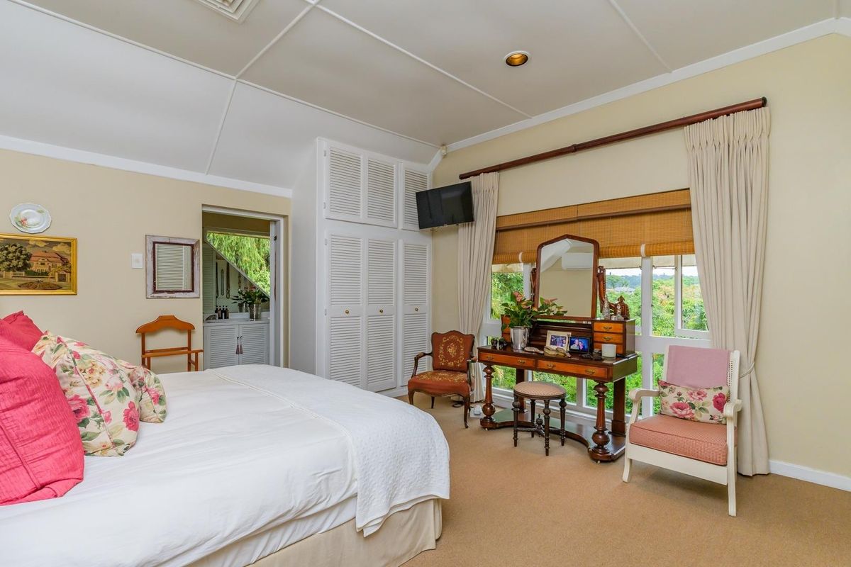 A well-lit bedroom featuring vaulted ceilings, built-in storage cupboards, and carpeted flooring, with direct access to an adjoining space.