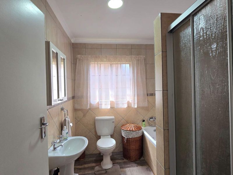 A functional bathroom featuring a pedestal basin, toilet, bathtub, and a separate shower enclosure with tiled wall finishes.