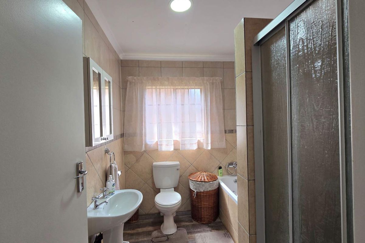 A functional bathroom featuring a pedestal basin, toilet, bathtub, and a separate shower enclosure with tiled wall finishes.