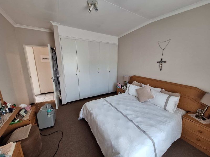 A carpeted bedroom featuring built-in cupboards and neutral wall finishes, providing a functional and comfortable sleeping space.