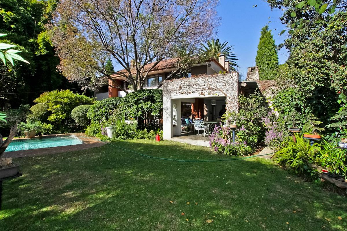 Rear view of the property featuring a landscaped garden, swimming pool, and a covered patio area.