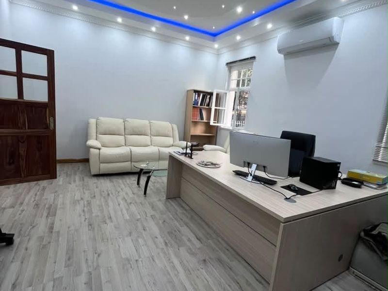 A modern office space featuring wood-look flooring, recessed ceiling lighting with blue LED accents, and a wall-mounted air conditioning unit.