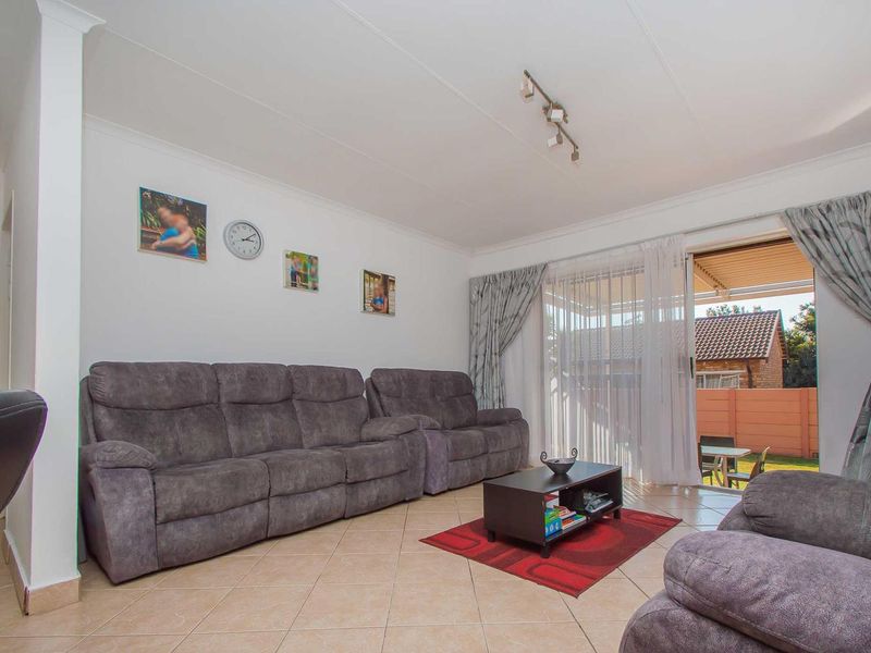 A comfortable living room featuring tiled flooring, track lighting, and a sliding glass door providing direct access to the outdoor patio area.