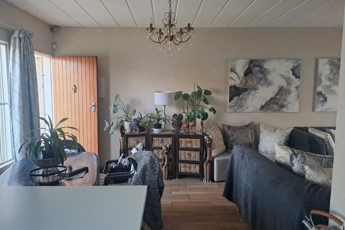 A living area featuring tiled flooring, a classic chandelier, and direct access to an exterior entrance door.