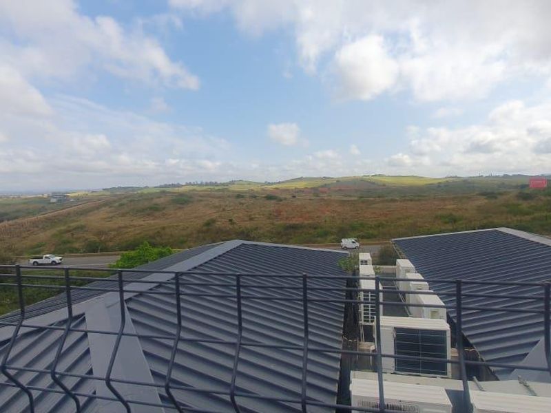 Elevated view overlooking the surrounding landscape and rolling hills, featuring modern metal roofing and external air conditioning units.