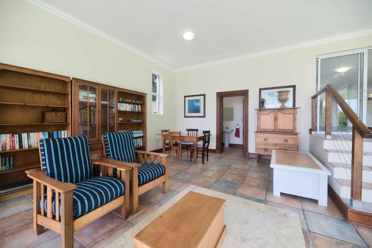 Spacious living area featuring terracotta floor tiles, crown molding, and a wooden staircase with a modern cable balustrade.