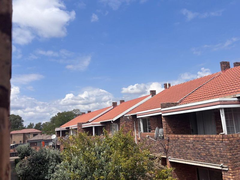 Exterior view of a residential apartment complex featuring face brick construction, terracotta tiled roofs, and private balconies.