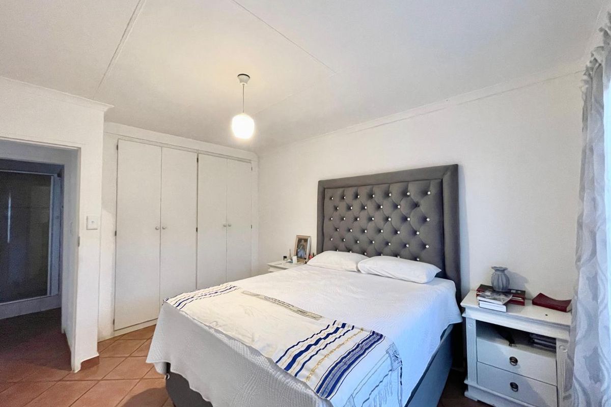 A bedroom featuring built-in cupboards, tiled flooring, and a central pendant light fixture.