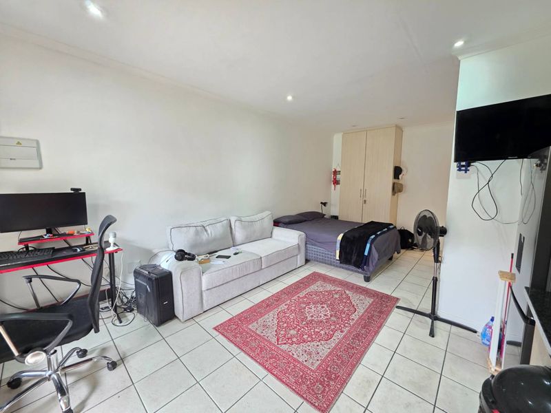 Open-plan studio apartment featuring tiled flooring, recessed lighting, and a built-in wardrobe, offering a functional living and sleeping space.
