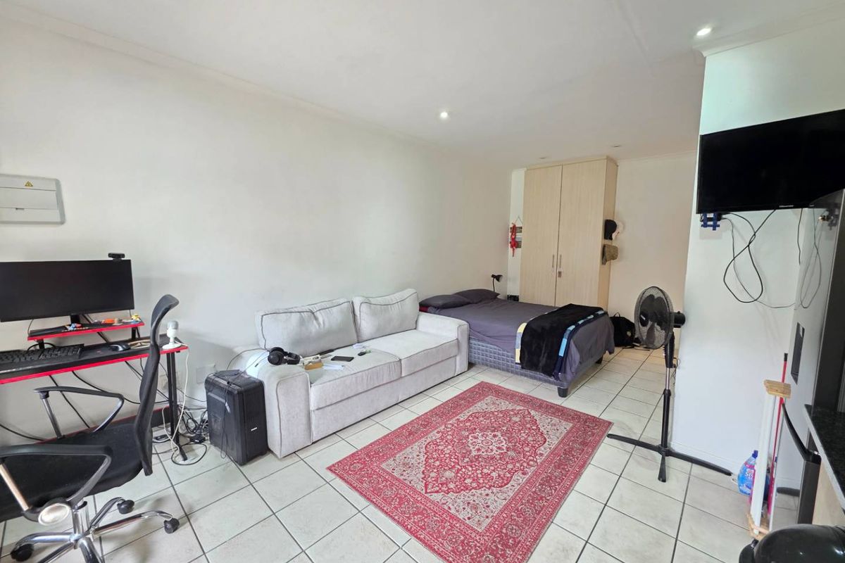 Open-plan studio apartment featuring tiled flooring, recessed lighting, and a built-in wardrobe, offering a functional living and sleeping space.