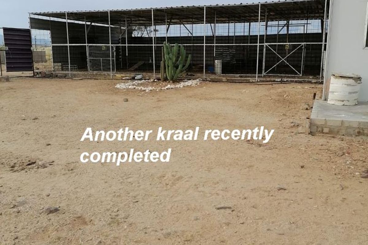 A newly constructed livestock kraal featuring a metal frame structure and wire mesh fencing, situated on a cleared dirt lot.