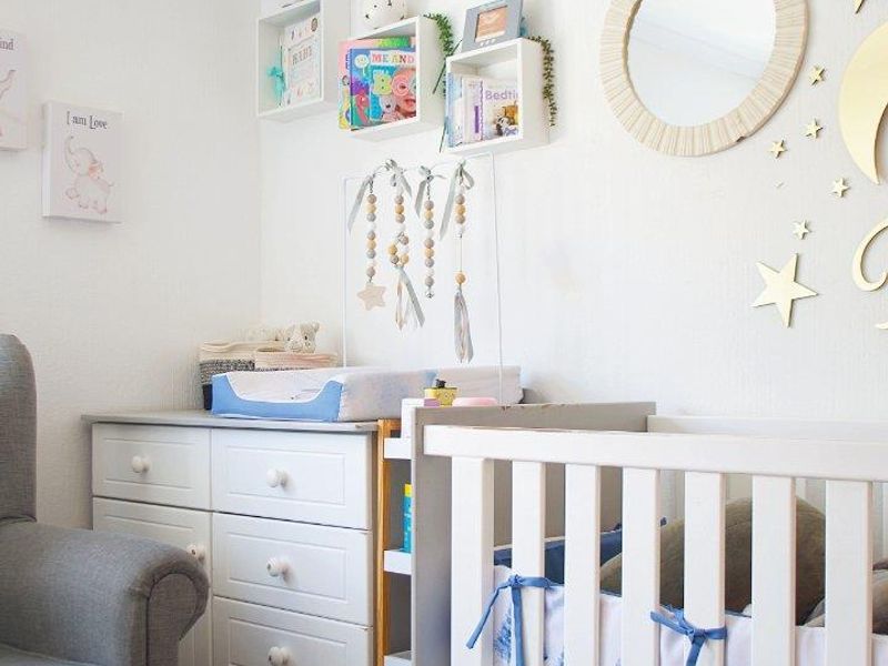 A well-maintained nursery bedroom featuring neutral wall finishes and built-in wall shelving, creating a bright and functional space.