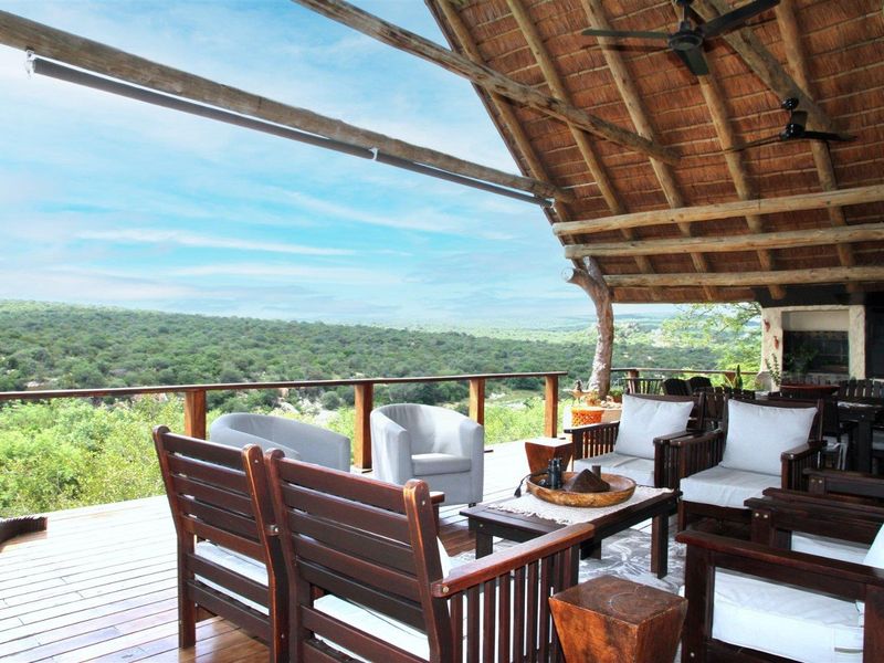 Spacious covered patio featuring a traditional thatched roof, exposed timber rafters, and expansive views over the surrounding landscape.