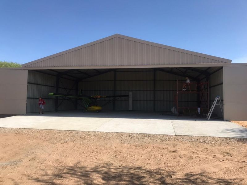 A large, modern steel-framed hangar or garage structure with a concrete floor, suitable for aircraft or heavy equipment storage.