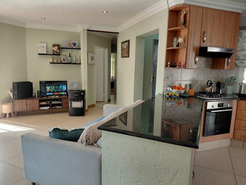 Open-plan living area featuring a kitchen with granite countertops, built-in oven, and gas hob, seamlessly flowing into the adjacent lounge space.
