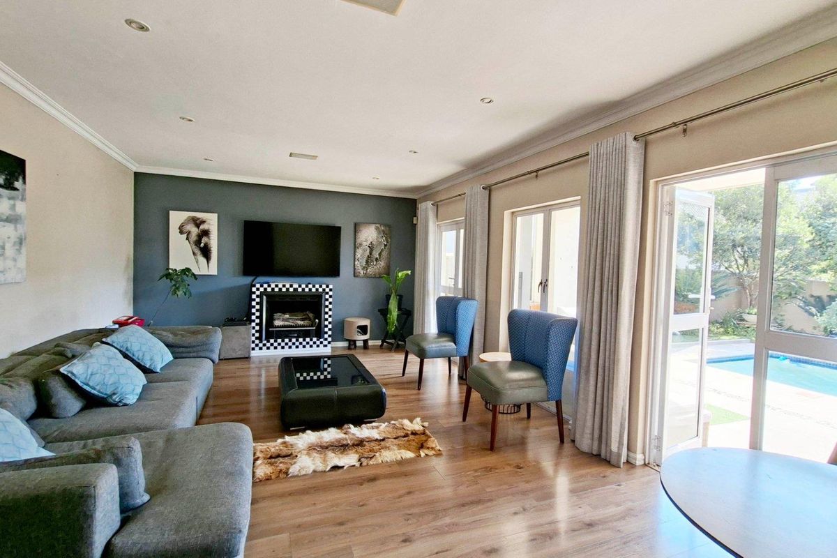 Spacious living room featuring laminate flooring, a feature fireplace, and large sliding glass doors providing direct access to the outdoor pool area.
