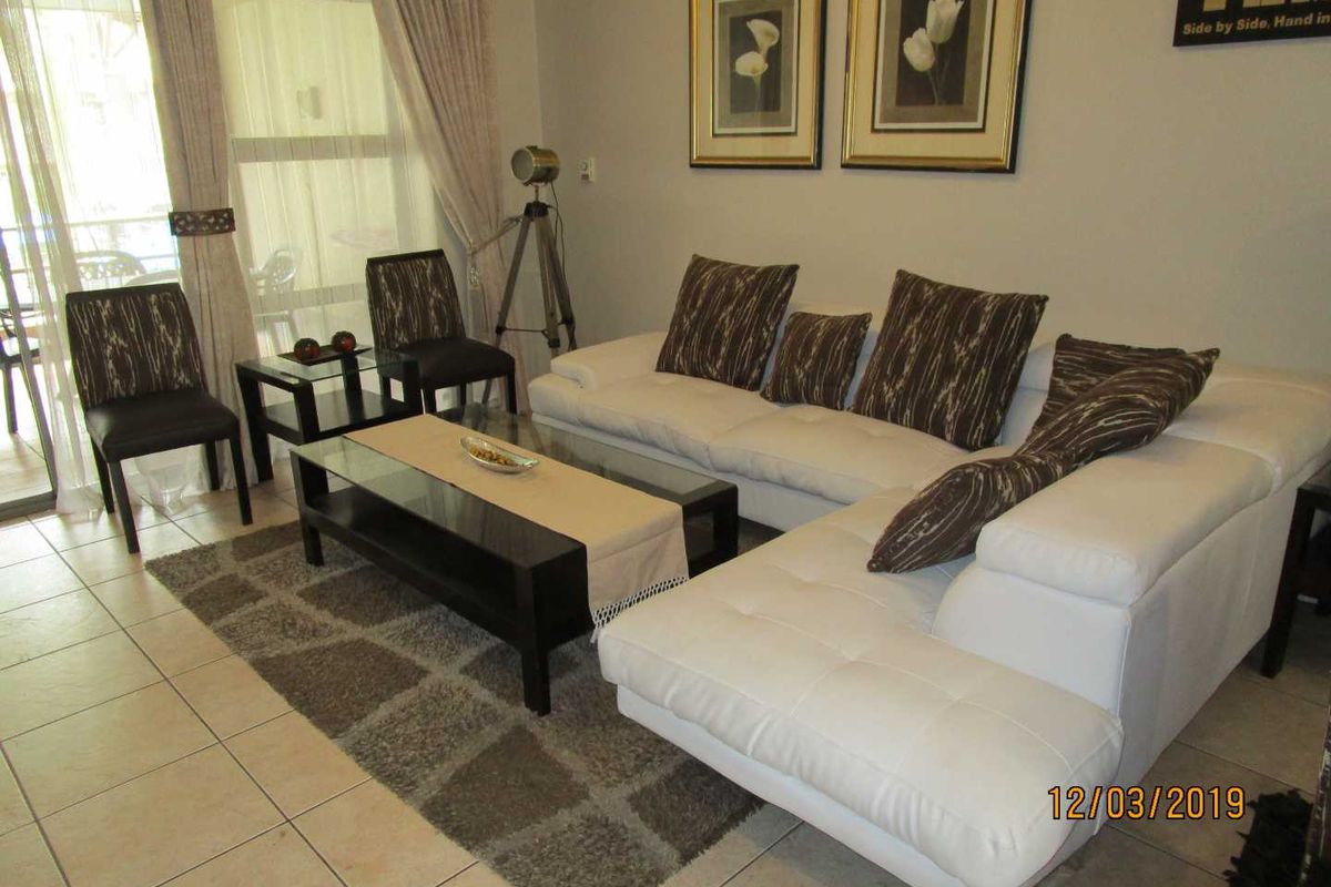 A living room area featuring tiled flooring and a sliding glass door providing access to an outdoor space.