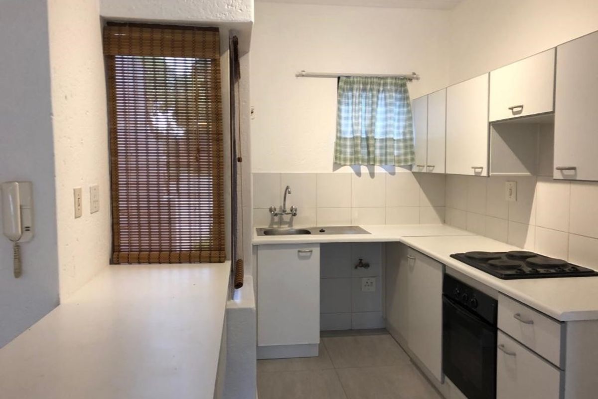 A functional kitchen featuring built-in cabinetry, a stainless steel sink, an integrated oven, and an electric hob with a tiled backsplash.