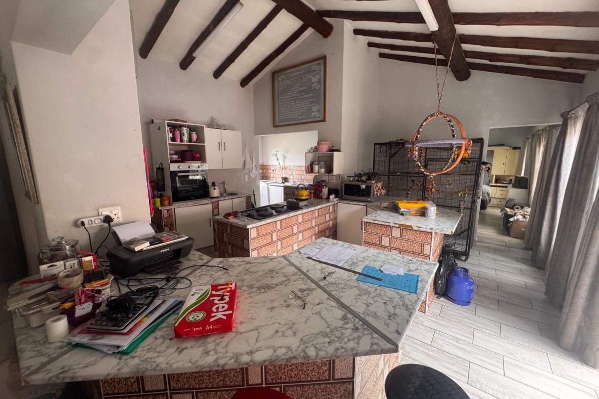 Spacious kitchen featuring exposed timber ceiling beams, tiled island units, and marble-look countertops, offering a rustic aesthetic with potential for modern updates.