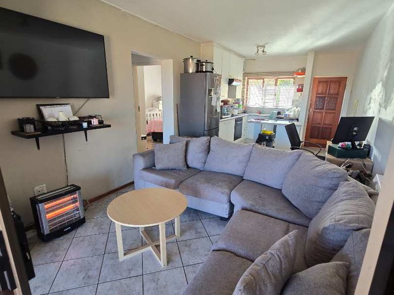 Open plan living area featuring tiled flooring, flowing into a functional kitchen space with built-in cabinetry and appliances.