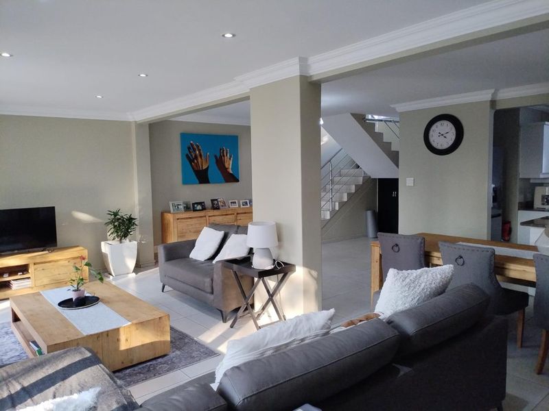 Spacious open-plan living area featuring neutral walls, recessed lighting, crown molding, and a central staircase with a modern metal balustrade.