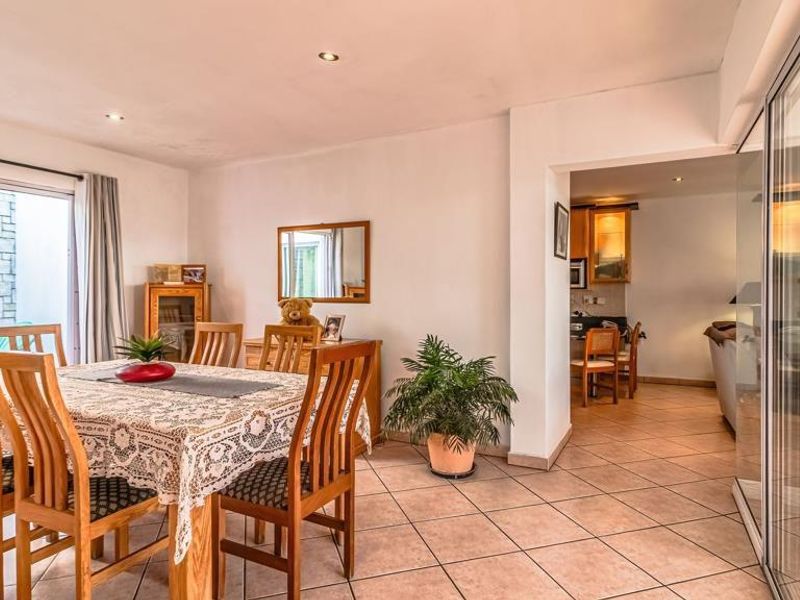 Open-plan dining area featuring tiled flooring, recessed lighting, and sliding glass doors leading to an outdoor patio, with an adjacent kitchen visible.