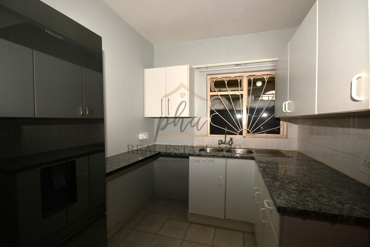 A functional kitchen featuring granite countertops, white cabinetry, a double-basin sink, and a window with a decorative security gate.